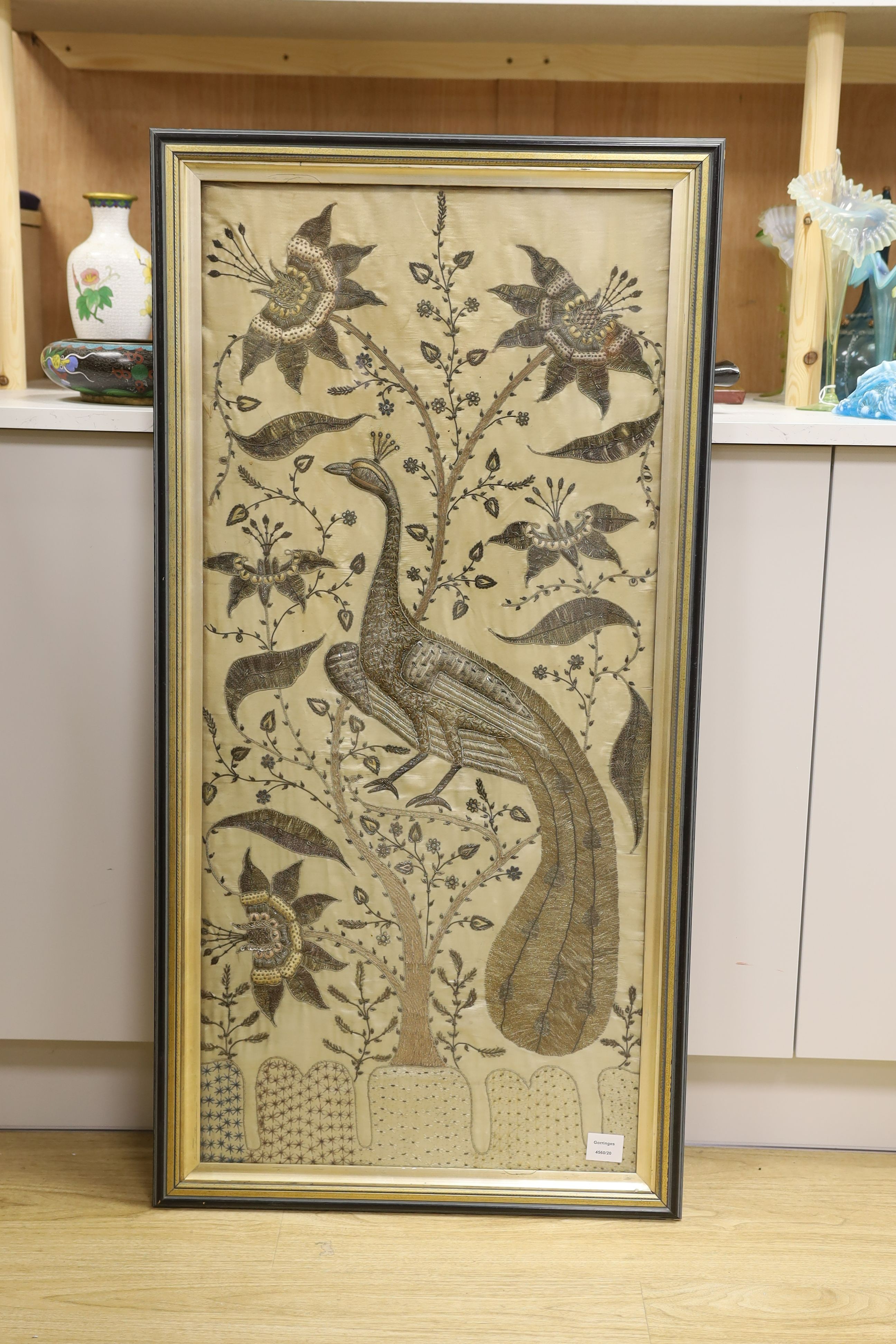 A framed large 19th century Indian embroidered panel decorated with a peacock and flowers 108x49cm